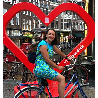 Woman on bike in front of a heart statue in a city