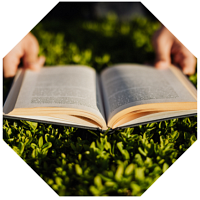Hands holding a book open on the grass