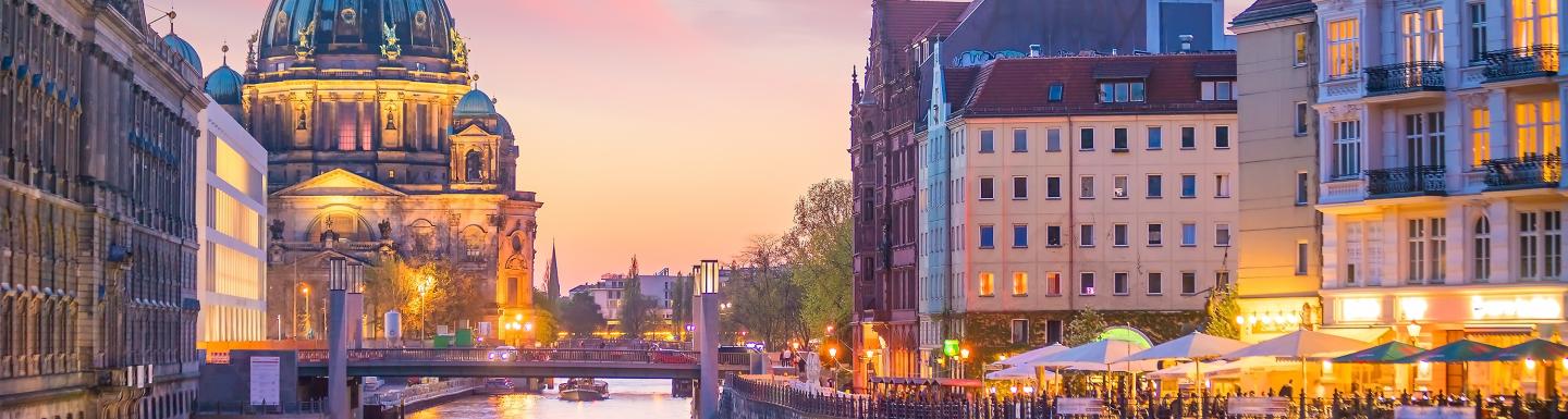 Evening view of Berlin canal at sunset, with historic buildings lining both sides.
