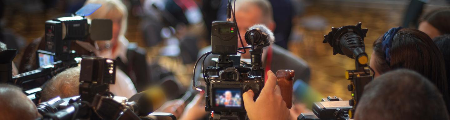 Group of journalists filming a press conference with large digital cameras