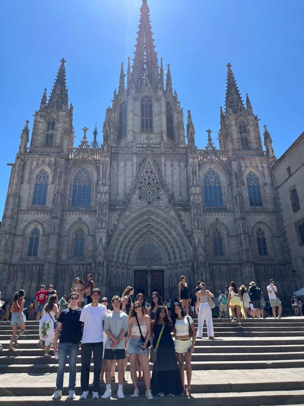 Ten students exploring Spain on a sunny day with Spanish architecture in the background