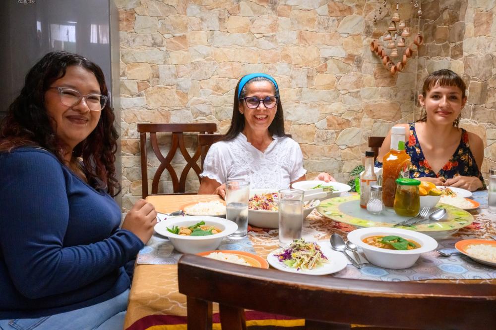 Three women sitting at a dinning room table with food