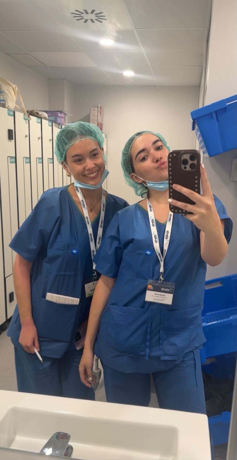 Lindsay taking a mirror selfie at work with another pre-med student in scrubs