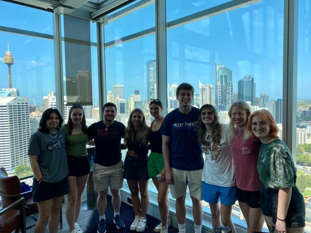 Group of college students smiling in front of a large building window in Australia