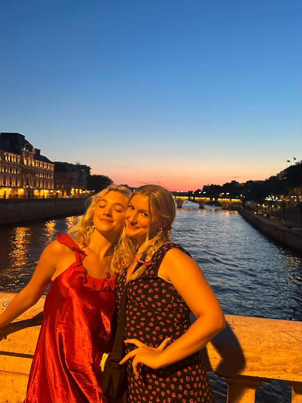 Katie smiling with their best friend by the river Seine during a sunset in Paris