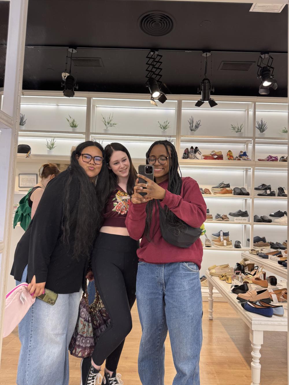 Three university students taking a mirror selfie in a shoe store