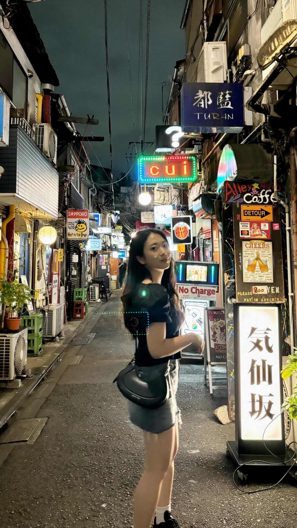 Evelyn smiling at night by shops on a street in Tokyo