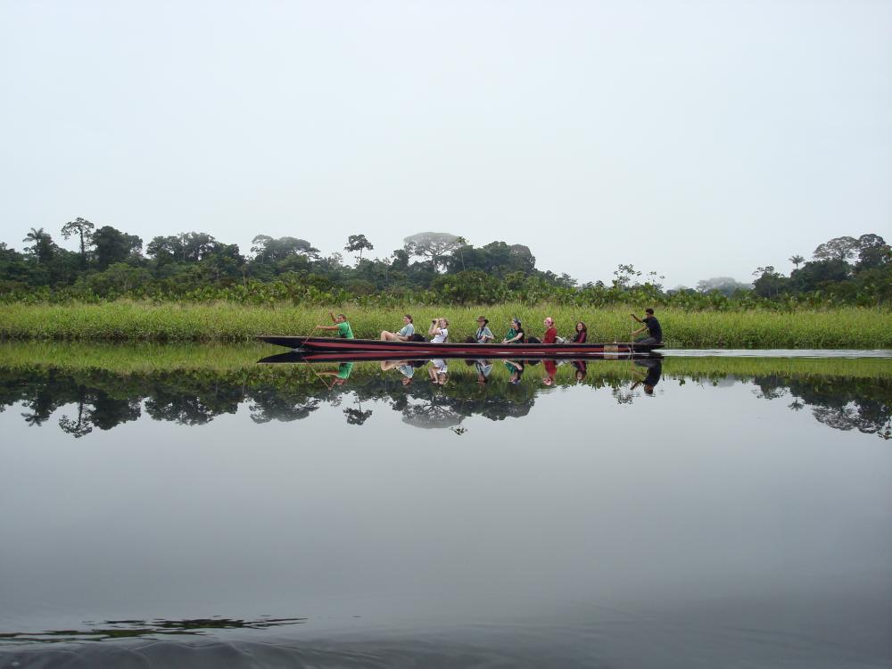 a group of students in a long canoe in the Amazon river