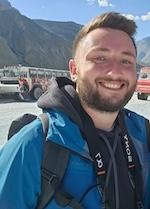 Daniel headshot smiling with a backpack on