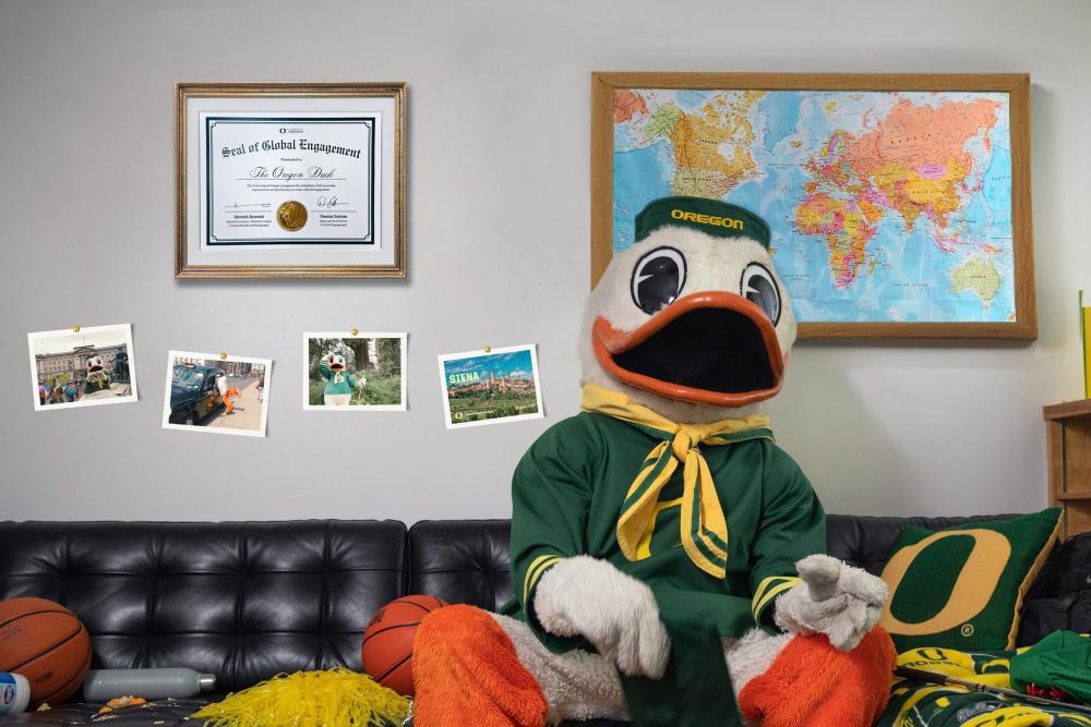 The Oregon Duck sitting on a leather couch in front of GEO posters, the world map and a seal of global engageemnt
