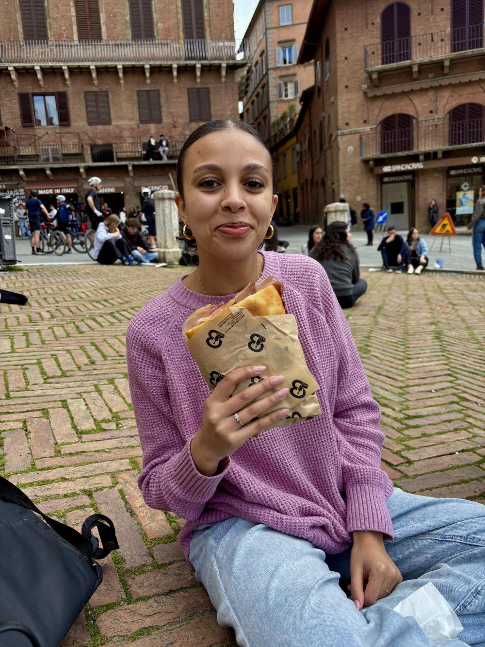 University student Sarah sitting in the Piazza del Campo holding focaccia bread