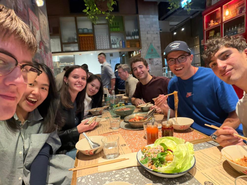 8 people sit around a dinner table and smile at the camera