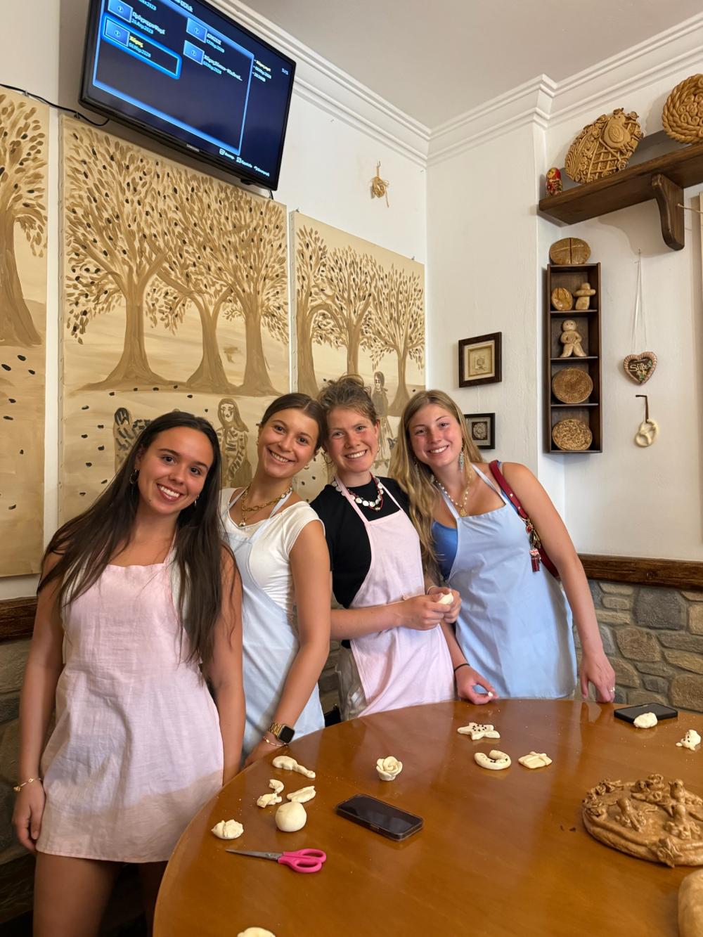 four college students wearing aprons making shapes with clay