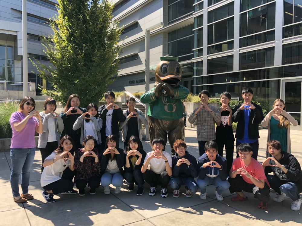 Group of students throwing standing in front of the Oregon Duck statue
