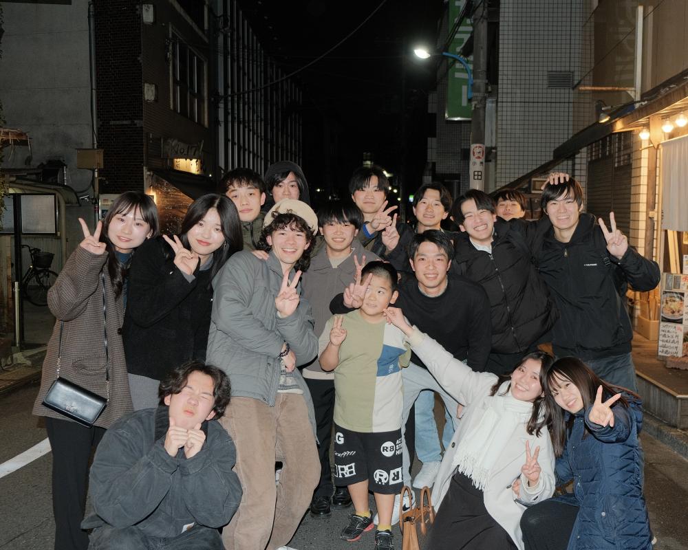 Large group of students in Japan posing for a picture holding up peace signs. 