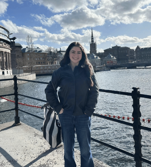 Ava standing in front of a river in Stockholm under a partly cloudy sky