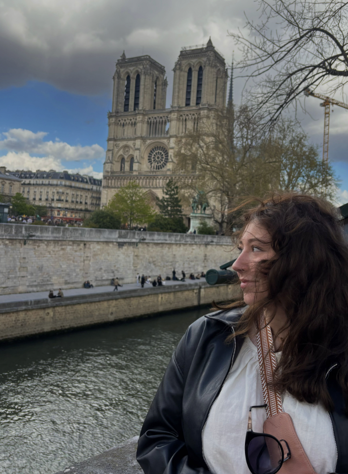 Giana looking out to the distance on a river cruise in Paris with the Notre Dame in the background