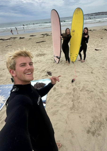 Calvin posing with a "hang loose" sign preparing to surf in Melbourne.