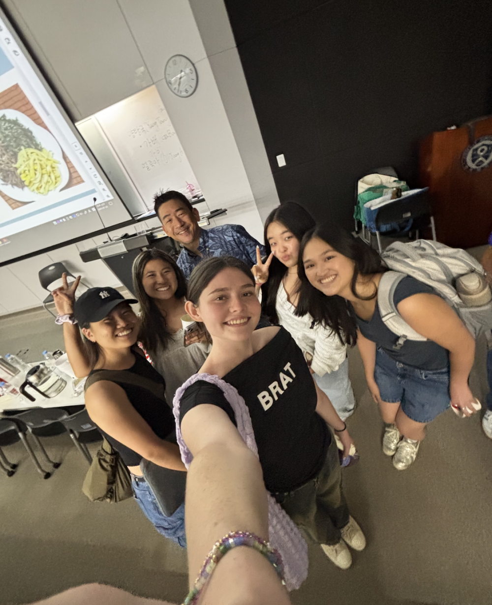 Six people gather in a classroom for a selfie photo
