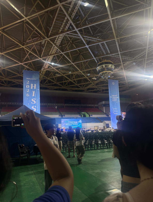 to big blue banners read "HISS", students are scattered through the frame at the orientation meeting