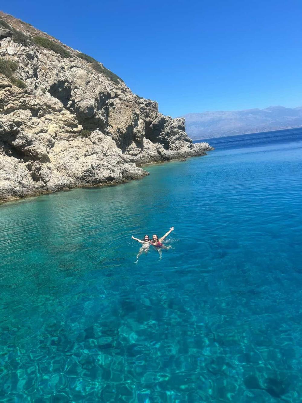 Two students swimming in the Mediterranean sea with their arms out