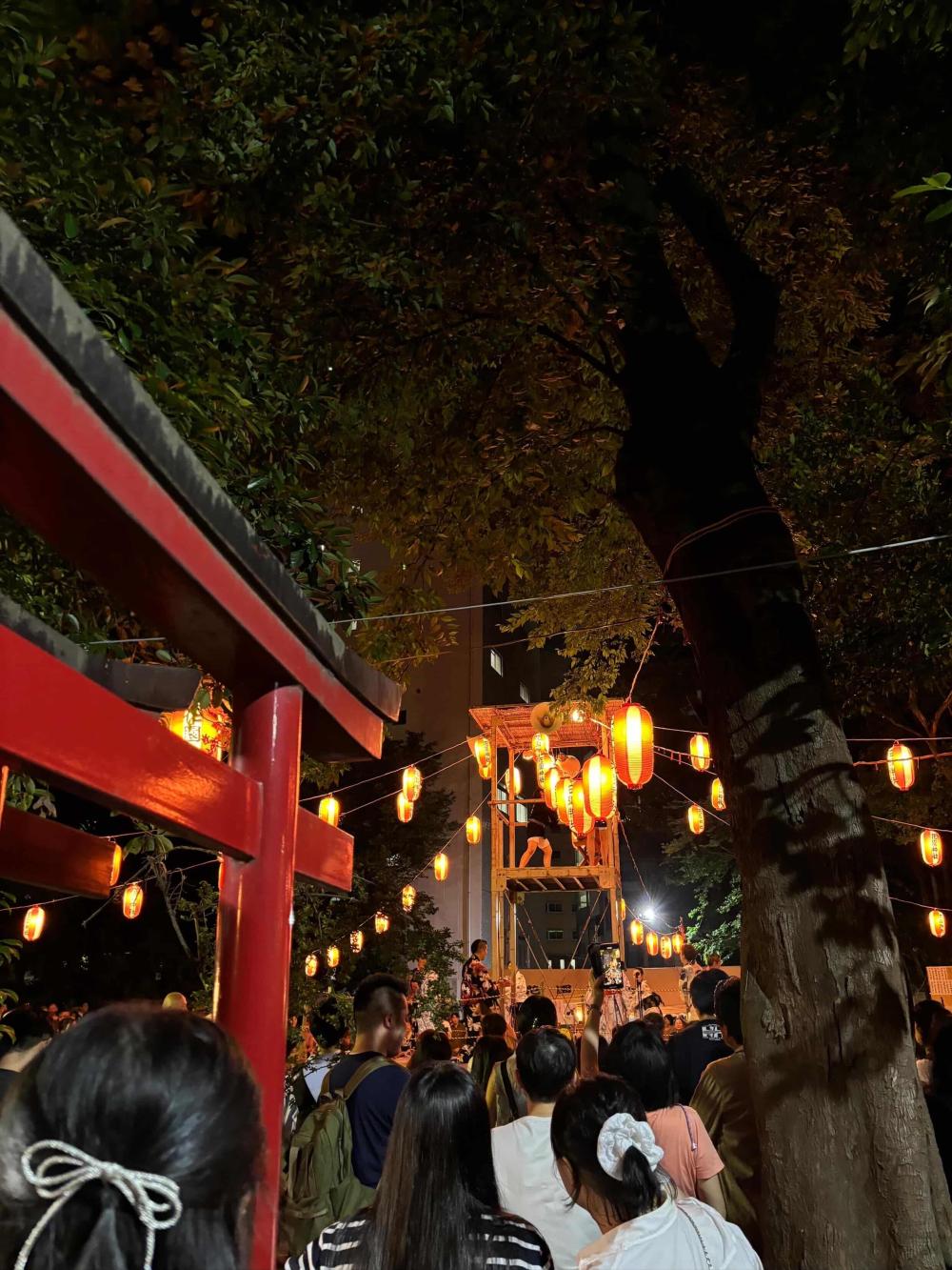 People walking in Tokyo at night with lanterns lighting the path