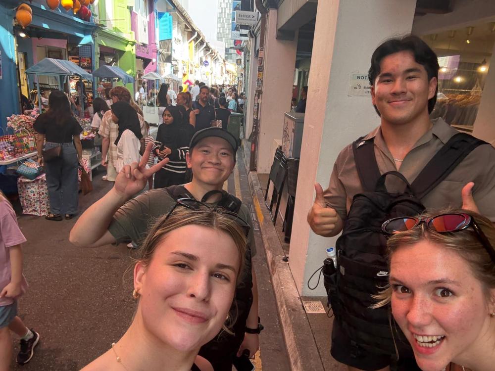 Logan and three other people pose for a picture in a crowded alley