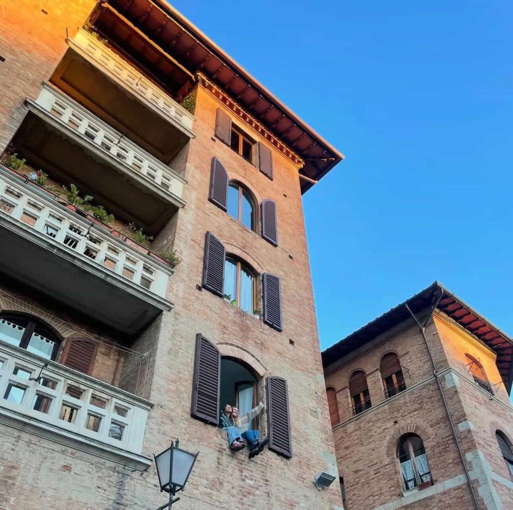 Siena building under a blue sky with open window shades