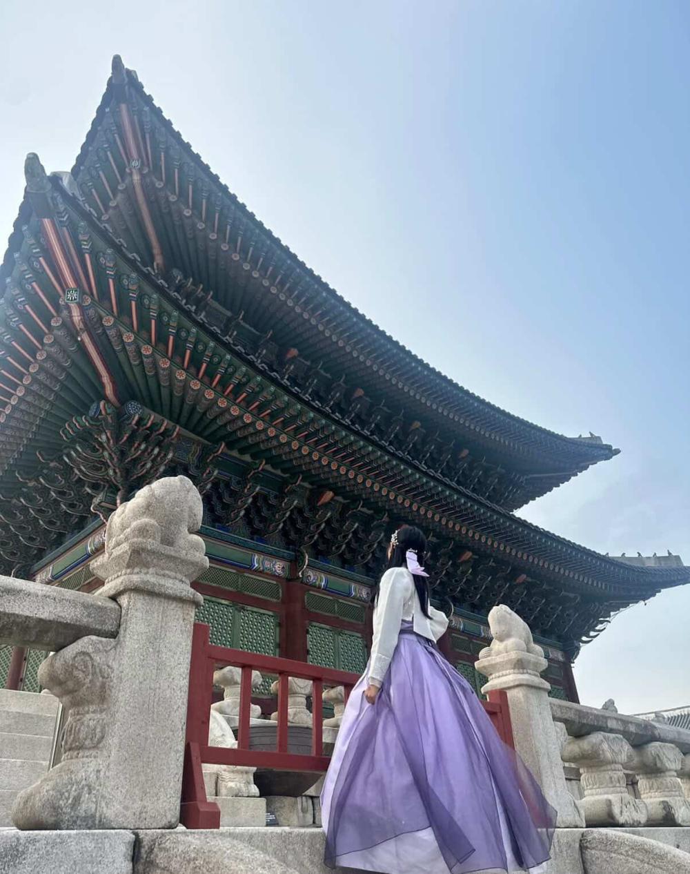 Vy walking up the steps of a Korean temple in a flowy purple skirt