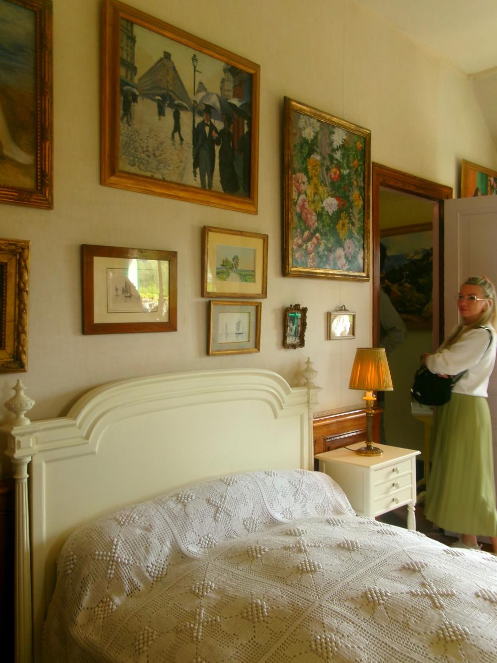 Inside view of Claude Monet's bedroom in France, with a tourist admiring the panintings