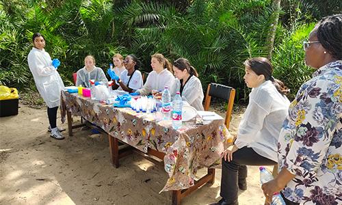 group of college students sitting at a table outside with medical supplies