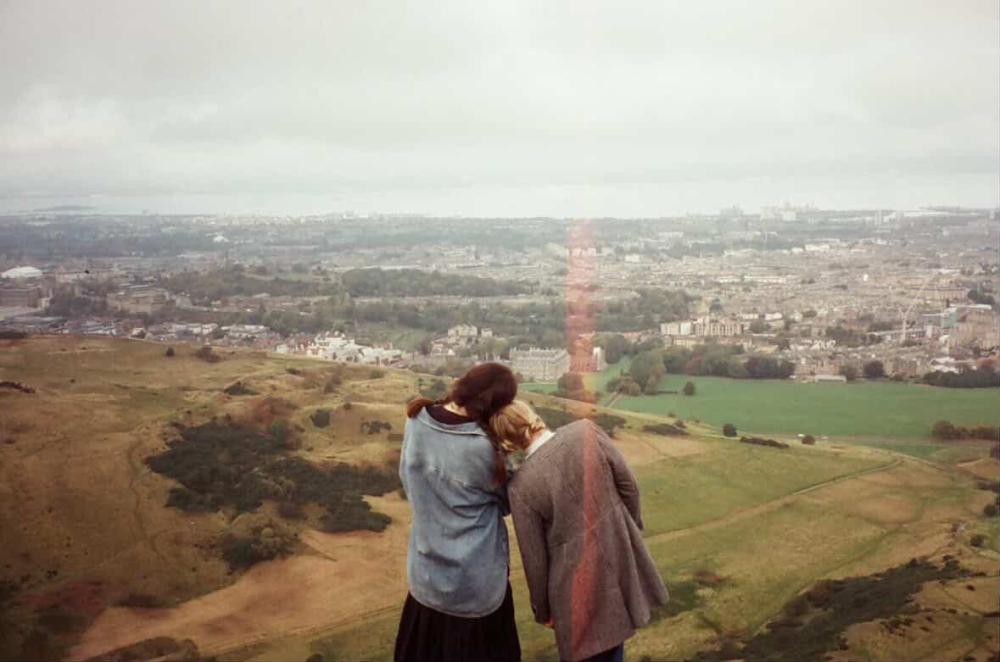 Film photo of one student resting their head on another student's shoulder in the English countryside