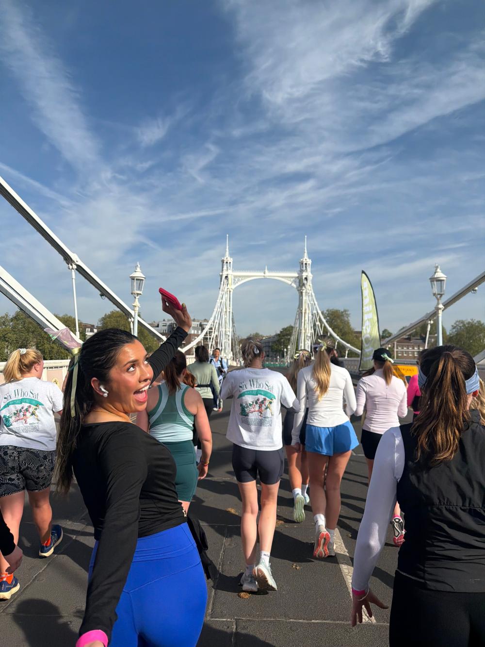 Group of people running at a London run club across a bridge on a sunny day