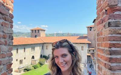 Person smiling inside the Castelvecchio in Verona with scenic views of historic buildings and skyline in the background.