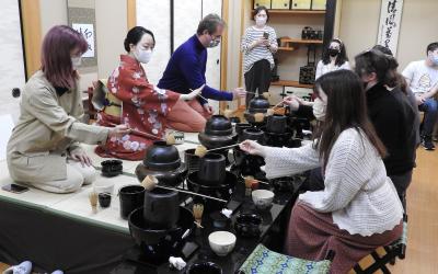 A group of people participating in a traditional Japanese tea ceremony in a tatami-matted room.