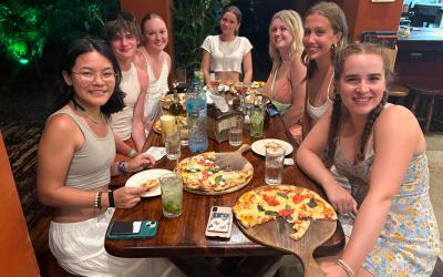 Lane and 6 friends sitting at a table eating pizza