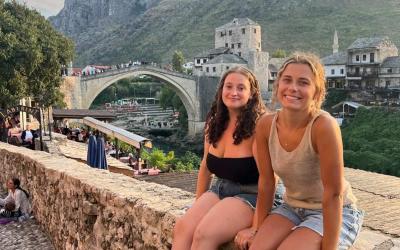Maya smiling with another student on a cobblestone bridge in Europe