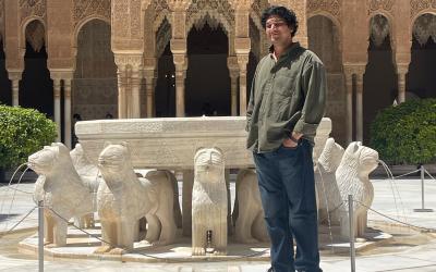 Kunal smiling by a courtyard with lion statues in Spain