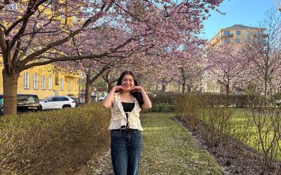 Ava smiling under a cherry blossom tree in Stockholm, Sweden
