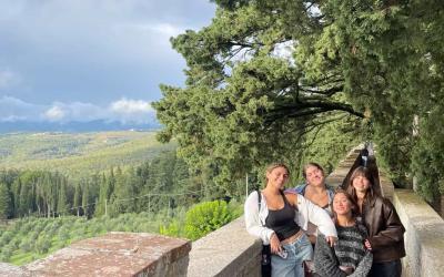 Gisele with three friends smiling on a walk in Italy under a shaded tree