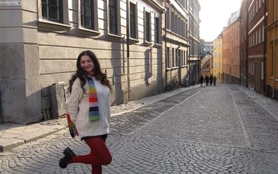 Ava smiling in the cobblestone streets of Stockholm, posing with one leg up 