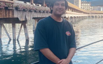 A student standing in front of castle and a lake