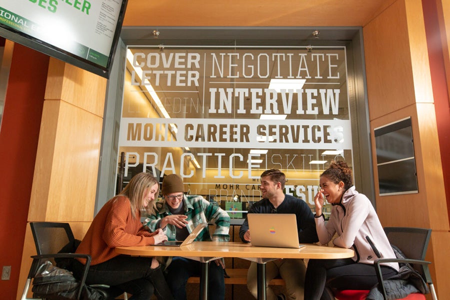 A group of students sitting, talking, and laughing at a table at the Career Center