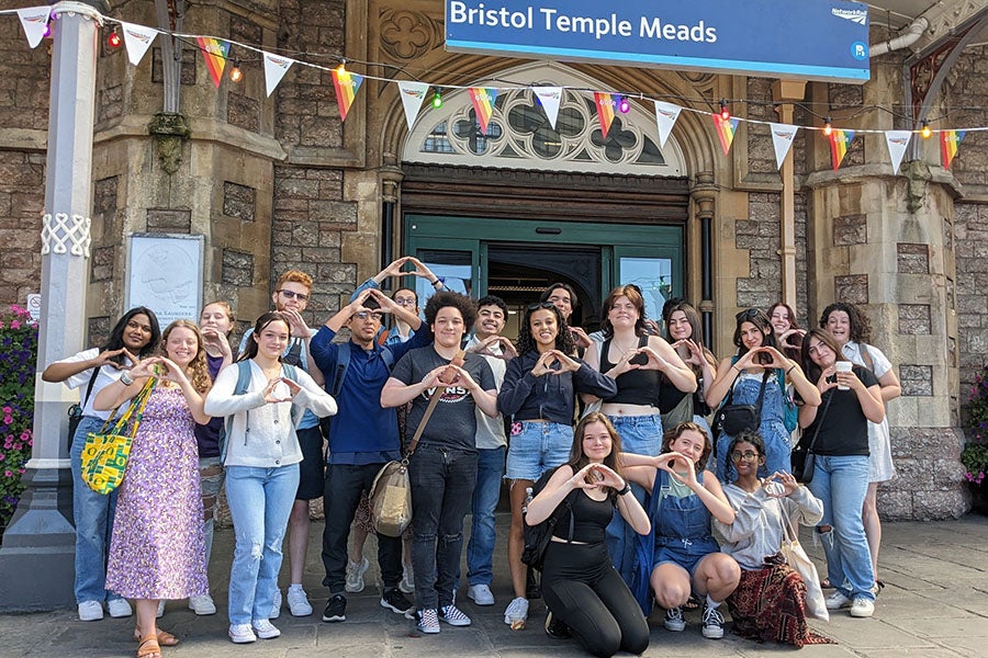 A group of UO students shooting the O while standing in front of a railway station