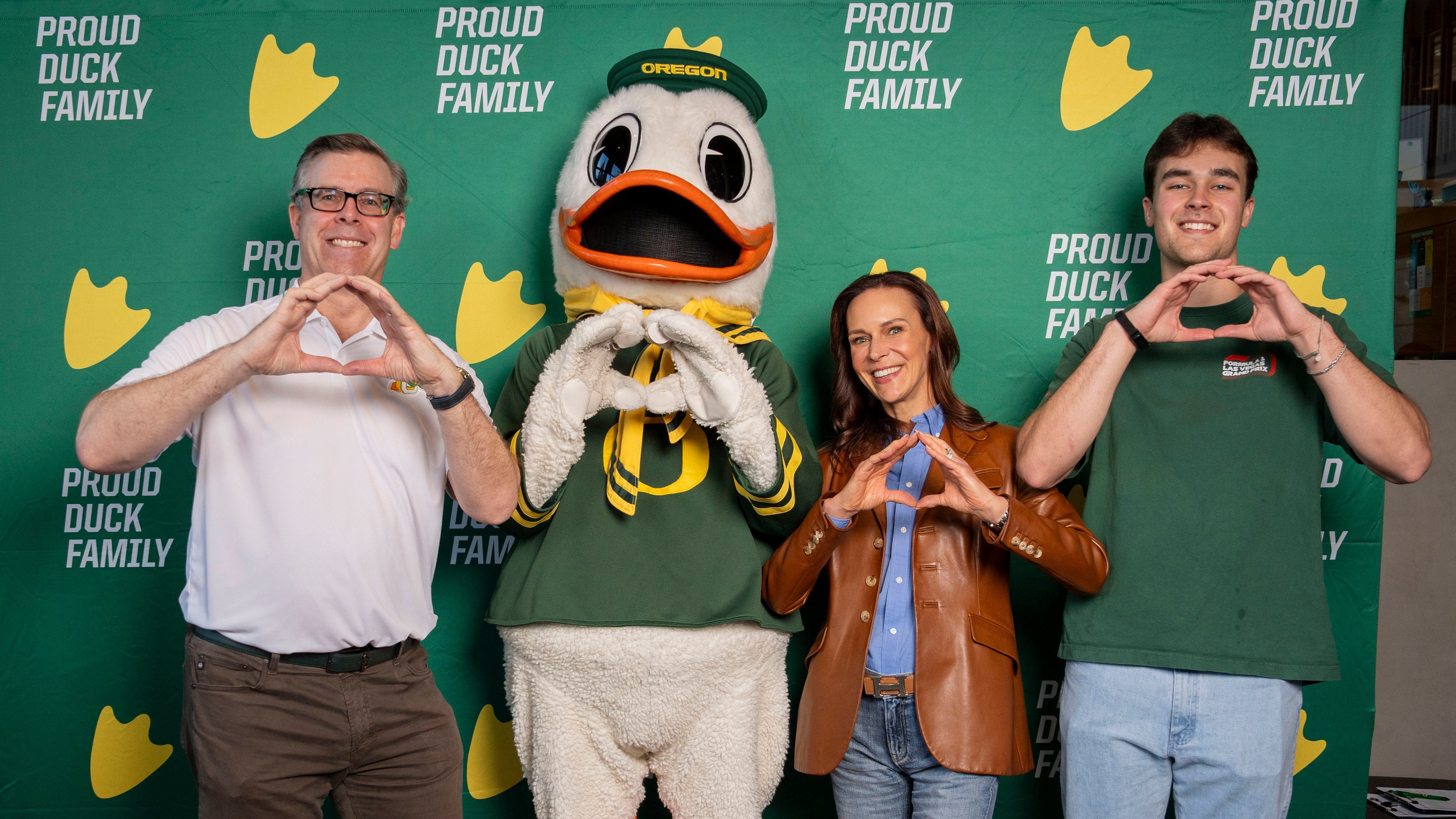Two parents and their son pose with the Oregon Duck mascot while shooting the Oregon O
