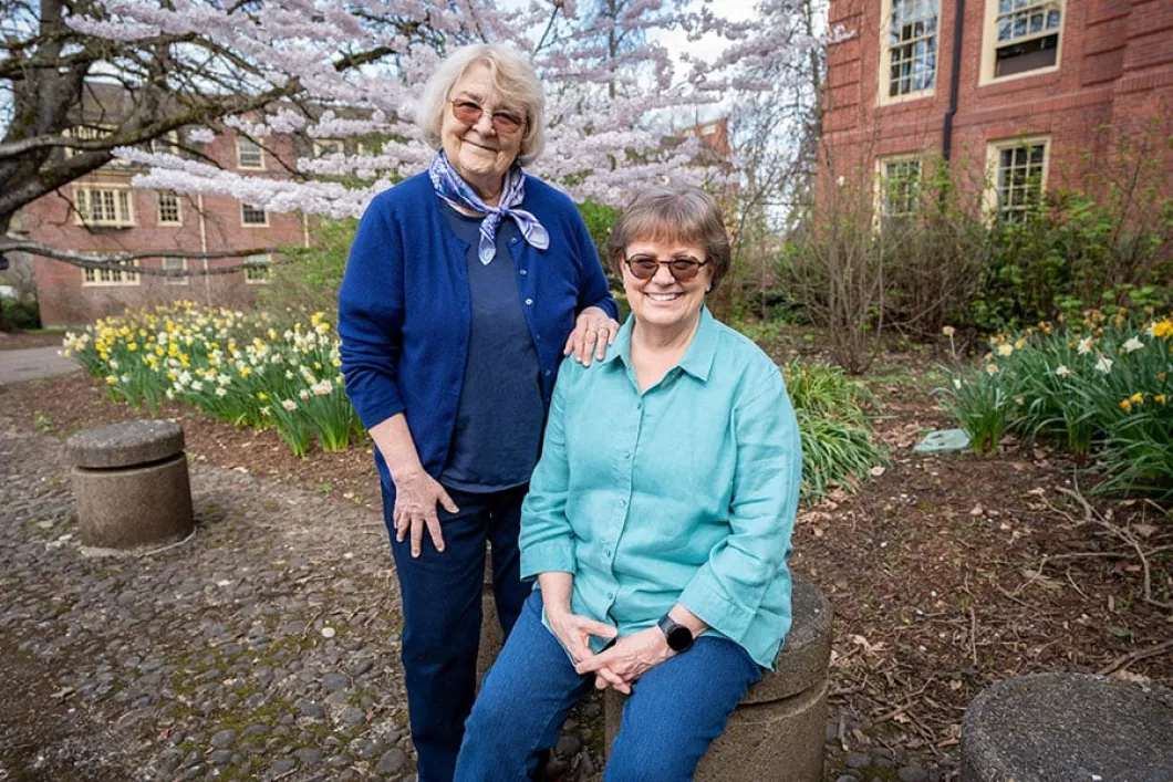 A female couple poses outdoors