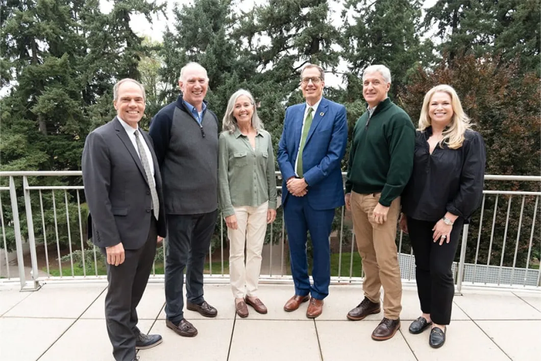 Donors to business school pose with the dean and university president outdoors