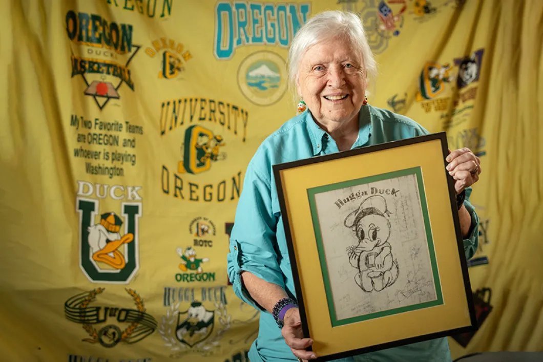 Elderly white woman holding a framed drawing of the Hugga Duck