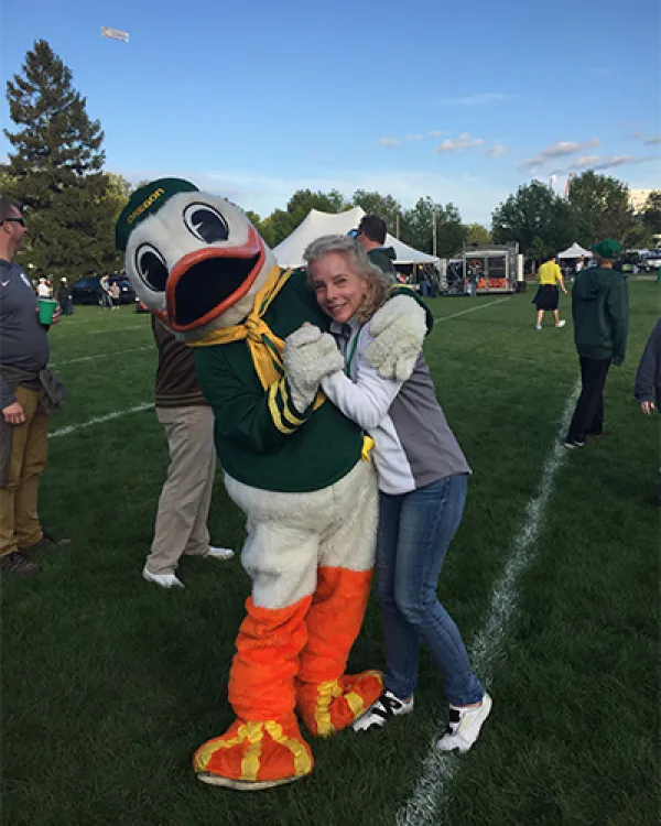 The Oregon Duck and Jamie Carr hugging outside a football tailgate