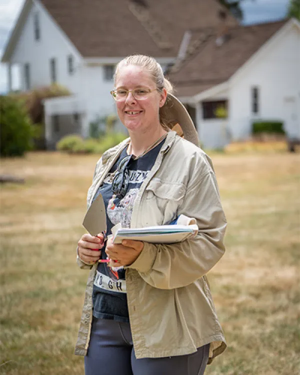 Blonde white woman standing outside in a tan jacket